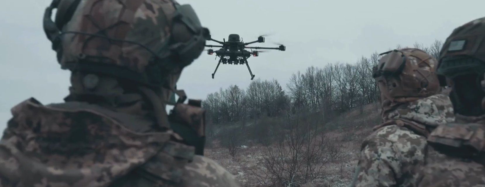 Soldiers watching a multirotor drone fly overhead
